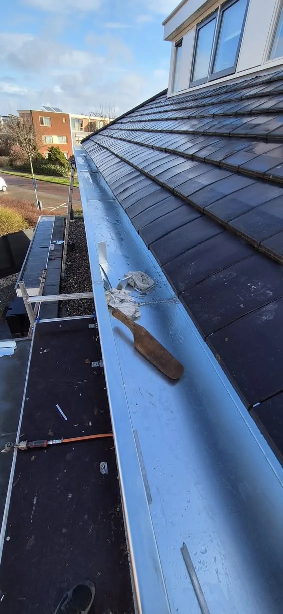 Nieuwe zinken goot langs een pannendak